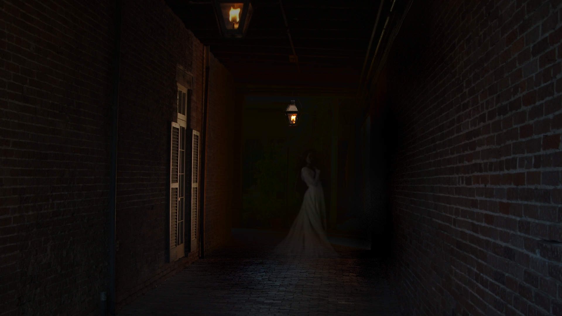 A lantern-lit brick carriage way at night with a pale figure standing at the far end